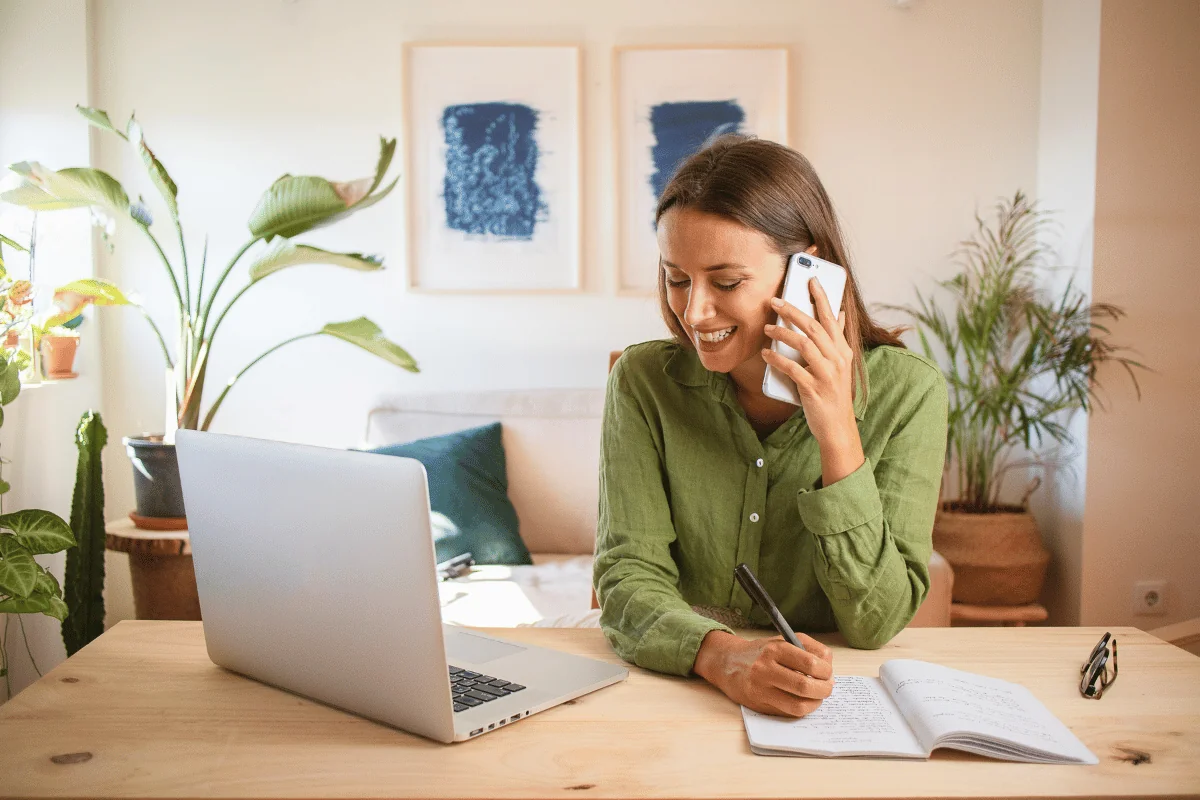 woman calling on phone with laptop and note on her desk